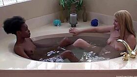 Ebony lesbian and blonde girlfriend relax in the tub.