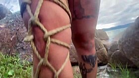 Shibari bondage performed in public with small tits exposed.