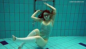 dasha dives underwater in a bikini, revealing her petite naked body by the pool