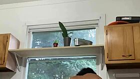 Latina milf enjoys washing dishes in the kitchen with a smile.