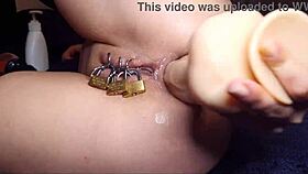 Caged pierced pussy locked while anal fisting stretches her wide