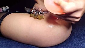 Caged pierced pussy locked while anal fisting stretches her wide