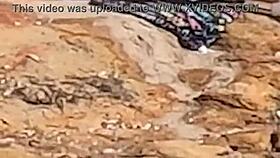 a beautiful young girl is WATCHED having sex in public on the beach rocks and INTERRUPTED by a third individual