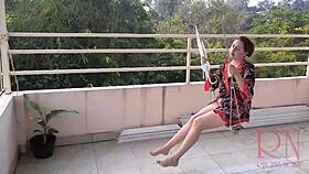 Depraved housewife swings naked under an umbrella in the rain. Full retro video of wild antics!