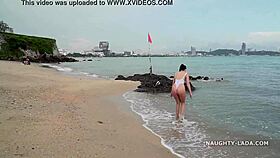 Milf wears see-through swimsuit on wet beach.