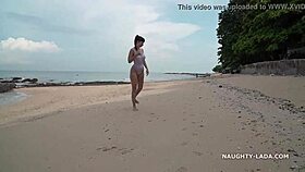 Milf wears see-through swimsuit on wet beach.