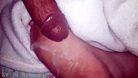 A close-up of oiled feet receiving a warm liquid splash.