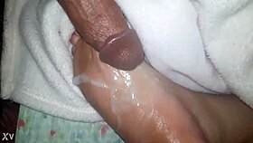 A close-up of oiled feet receiving a warm liquid splash.