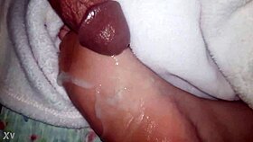 A close-up of oiled feet receiving a warm liquid splash.