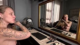 Sexy tattooed blonde girl does her hair and makeup naked