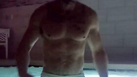 A muscular man soaks in public jacuzzi.