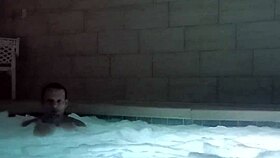 A muscular man soaks in public jacuzzi.