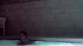 A muscular man soaks in public jacuzzi.
