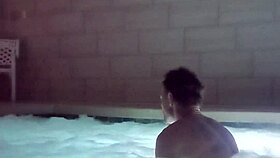 A muscular man soaks in public jacuzzi.