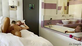 He strokes furiously in the tub while she grinds her dildo on the glass wall nearby