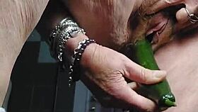Granny teases her hairy beaver with a cucumber